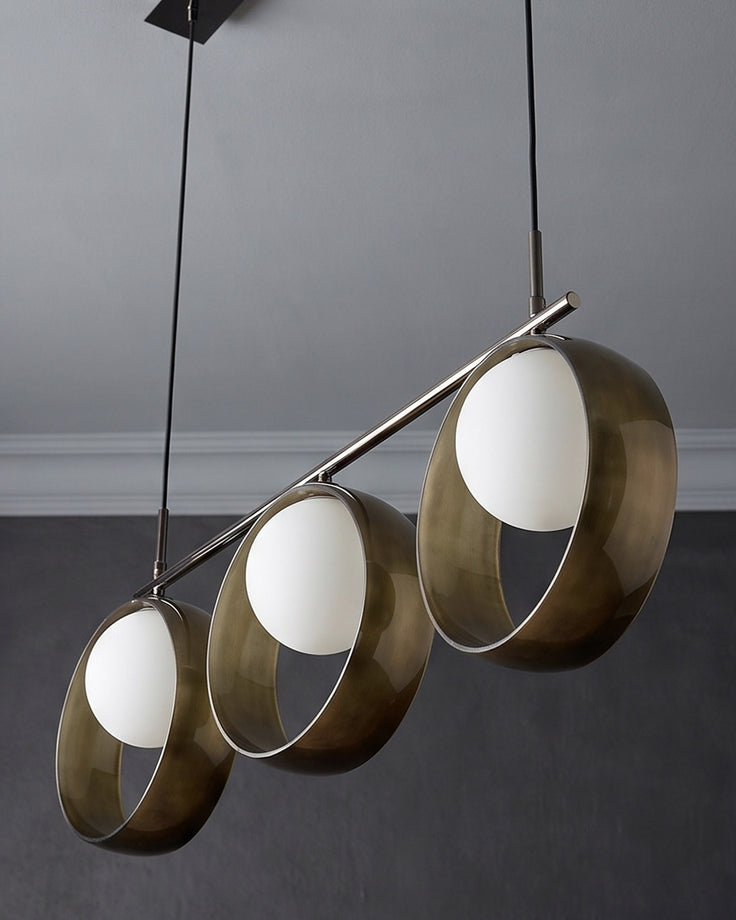 Chloe 3-pendant light with brushed brass cylindrical shades and frosted glass diffusers, suspended on thin cords at staggered heights.