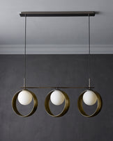 Chloe 3-pendant light with green metal rings and white spherical glass shades, suspended from dark ceiling fixture.