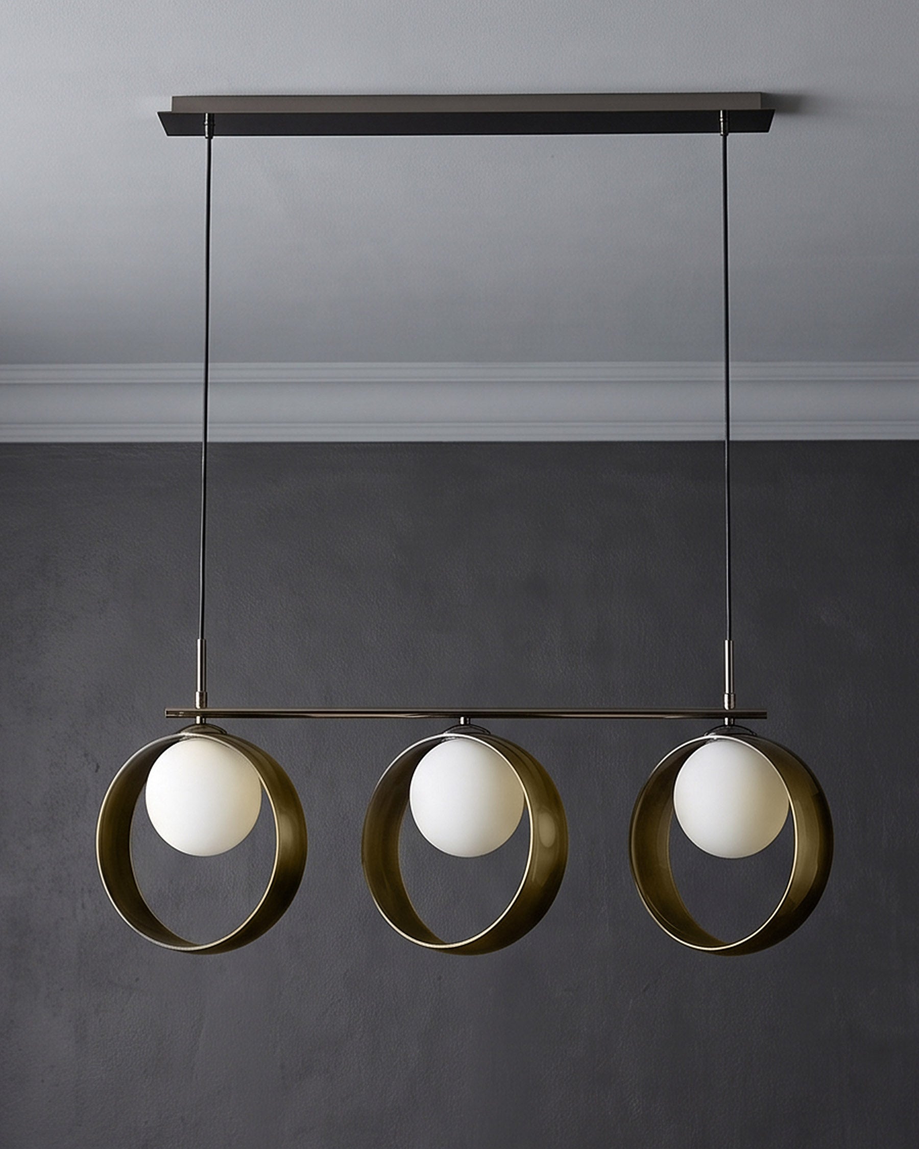Chloe 3-pendant light with green metal rings and white spherical glass shades, suspended from dark ceiling fixture.