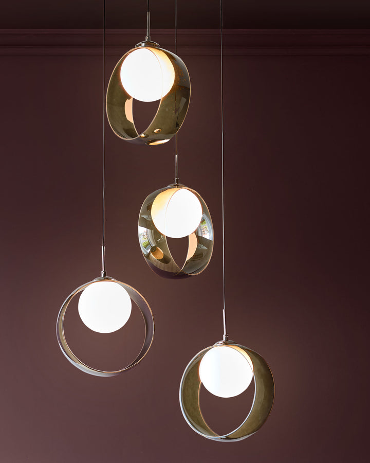 Chloe 4-pendant light with green glass shades and white spherical bulbs suspended against a burgundy wall.