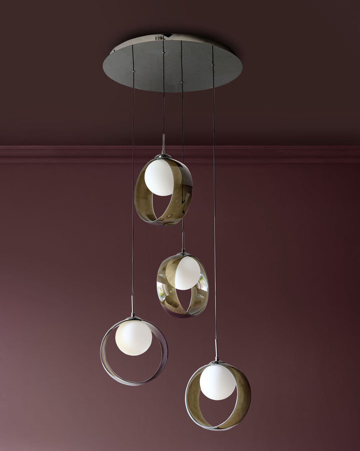 Chloe 4-pendant light with green glass spheres and brass orbital frames suspended from a grey ceiling canopy against a burgundy wall.