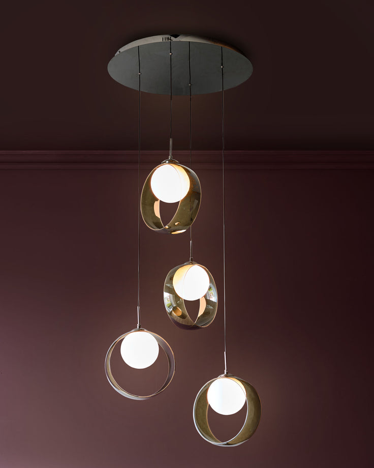 Chloe 4-pendant light with green glass spheres and brass accents, suspended from a ceiling canopy against a burgundy wall.