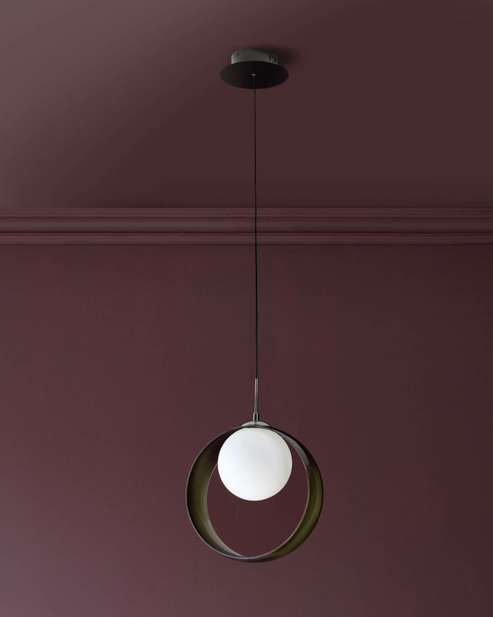 Chloe single pendant light with green glass circular shade and white frosted globe, suspended by thin metal cord against mauve wall.