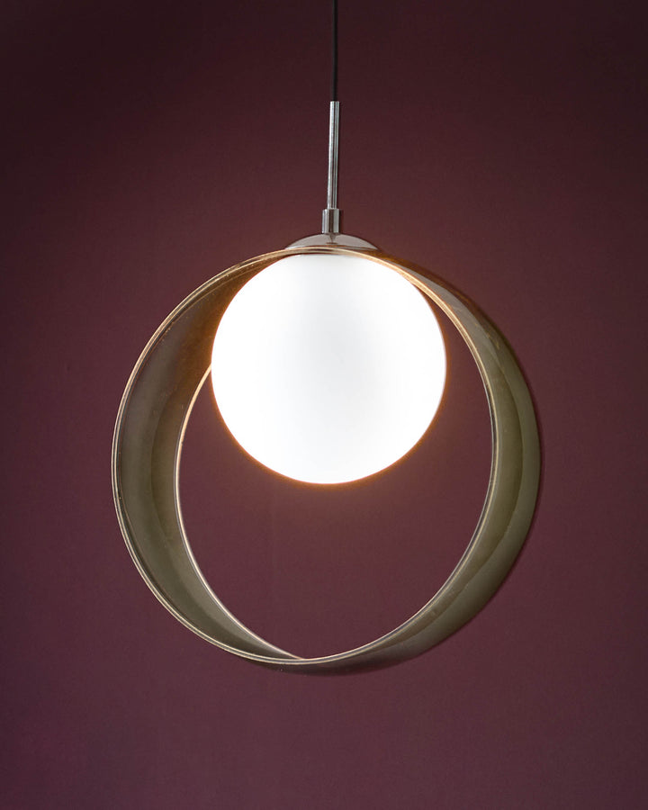 Green glass spherical pendant light with white glowing orb center, suspended against burgundy background.
