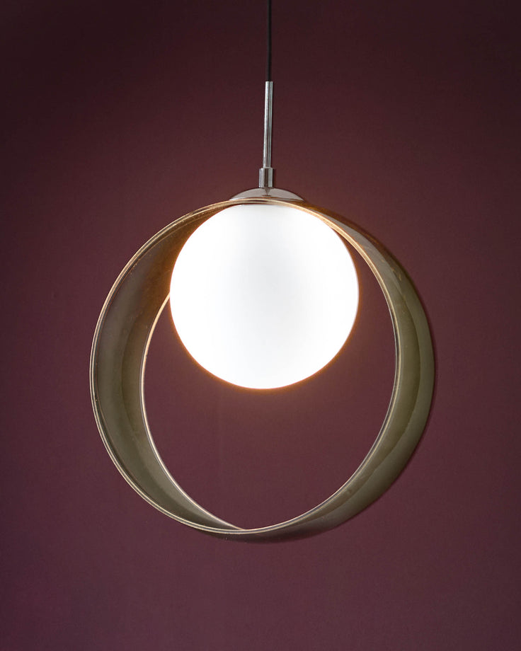 Green glass spherical pendant light with white glowing orb center, suspended against burgundy background.
