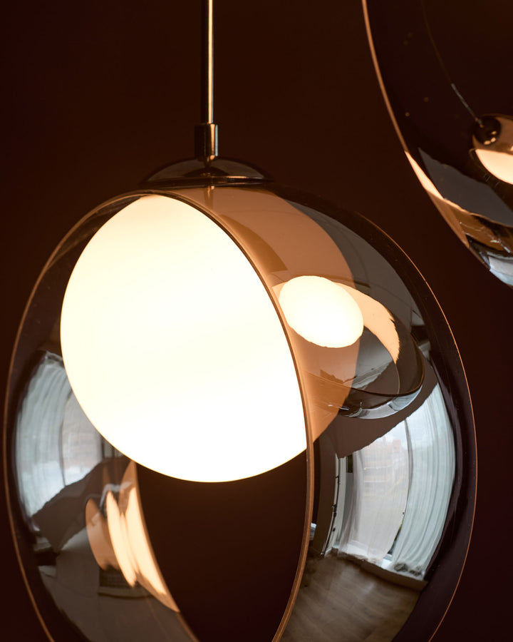 Chloe 4 pendant light with spherical glass shade, chrome finish, illuminated against dark background showing warm glow.