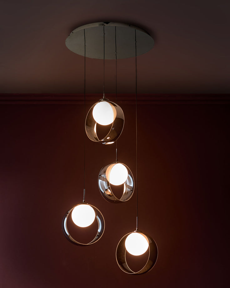 Chloe 4-pendant light with spherical chrome glass shades and white globes suspended from silver ceiling plate.