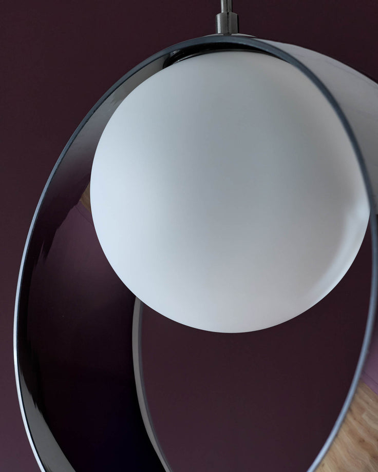 Chloe single pendant light with frosted white glass sphere and polished chrome frame, suspended against burgundy wall.