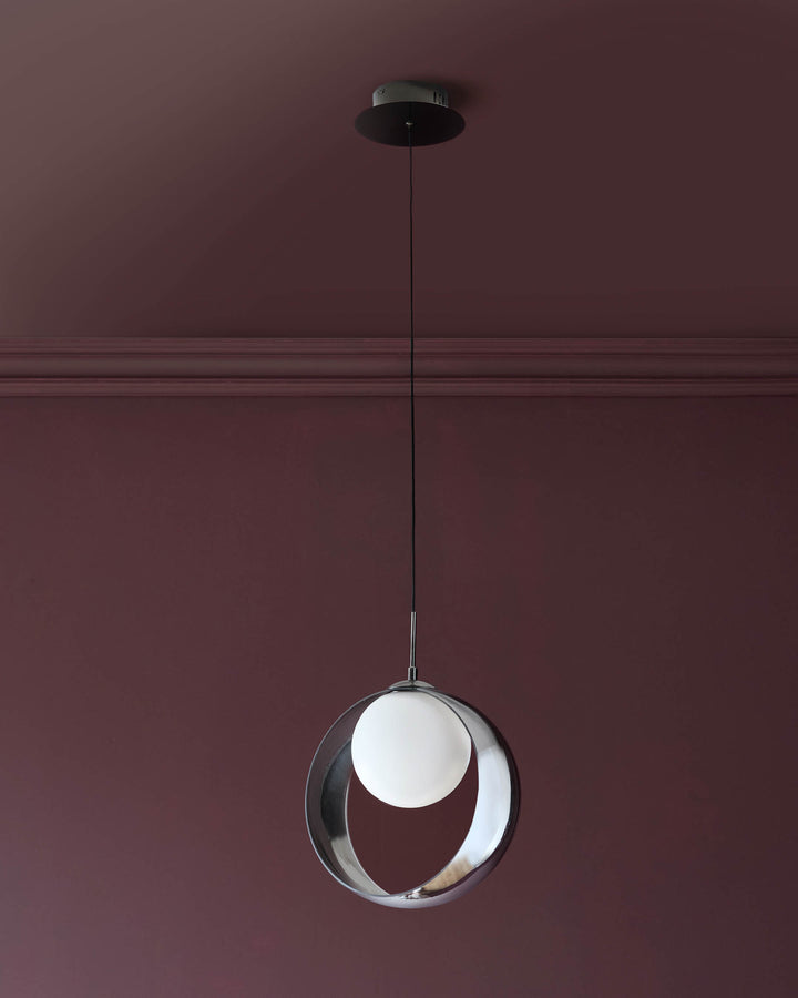 Chloe single pendant light with spherical glass shade in silver chrome finish, suspended from black cord against mauve wall.