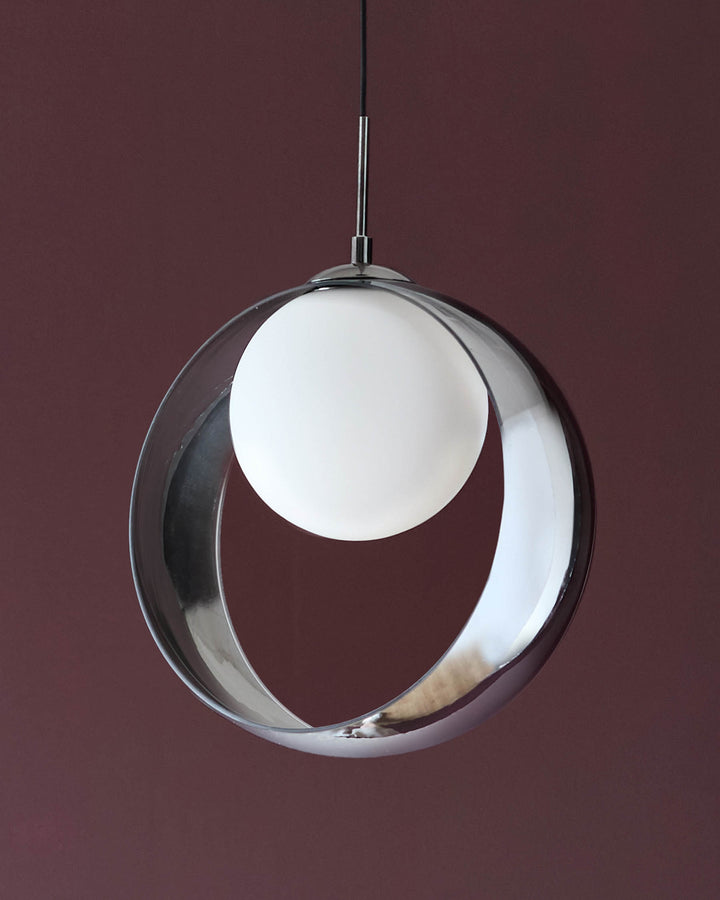 Chloe single pendant light with spherical clear glass shade and white orb inside, chrome finish hardware, against burgundy background.