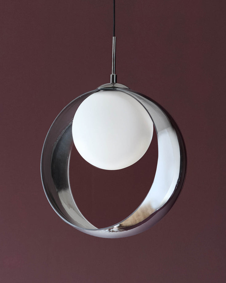 Chloe single pendant light with spherical clear glass shade and white orb inside, chrome finish hardware, against burgundy background.