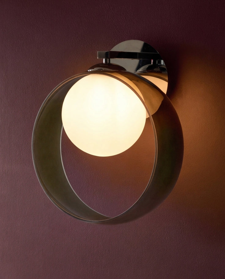 Chloe wall light with curved green glass shade and chrome mounting bracket, illuminated against burgundy wall.