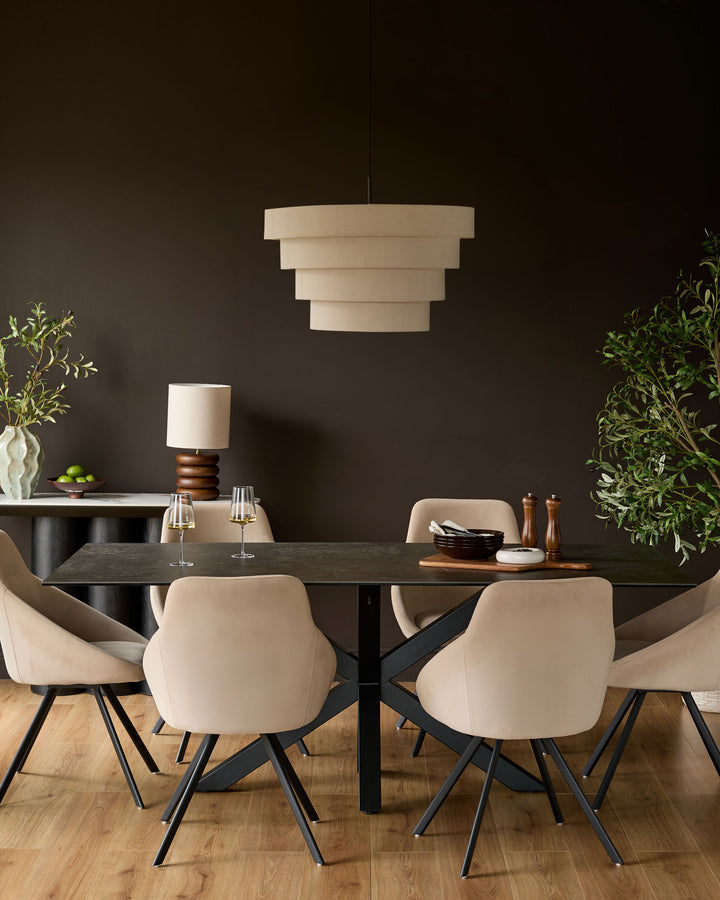 Champagne velvet swivel chair with curved back and black tapered legs, shown in dining room setting.