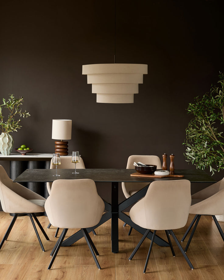 Champagne velvet swivel chair with curved back and black tapered legs, shown in dining room setting.