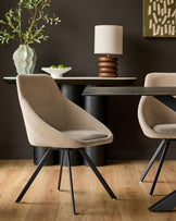 Champagne velvet swivel chair with curved bucket seat and black metal legs, shown in dining room setting.