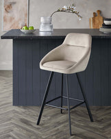 Stylish kitchen bar stool with a beige fabric seat and black metal legs. Modern design for a contemporary kitchen.