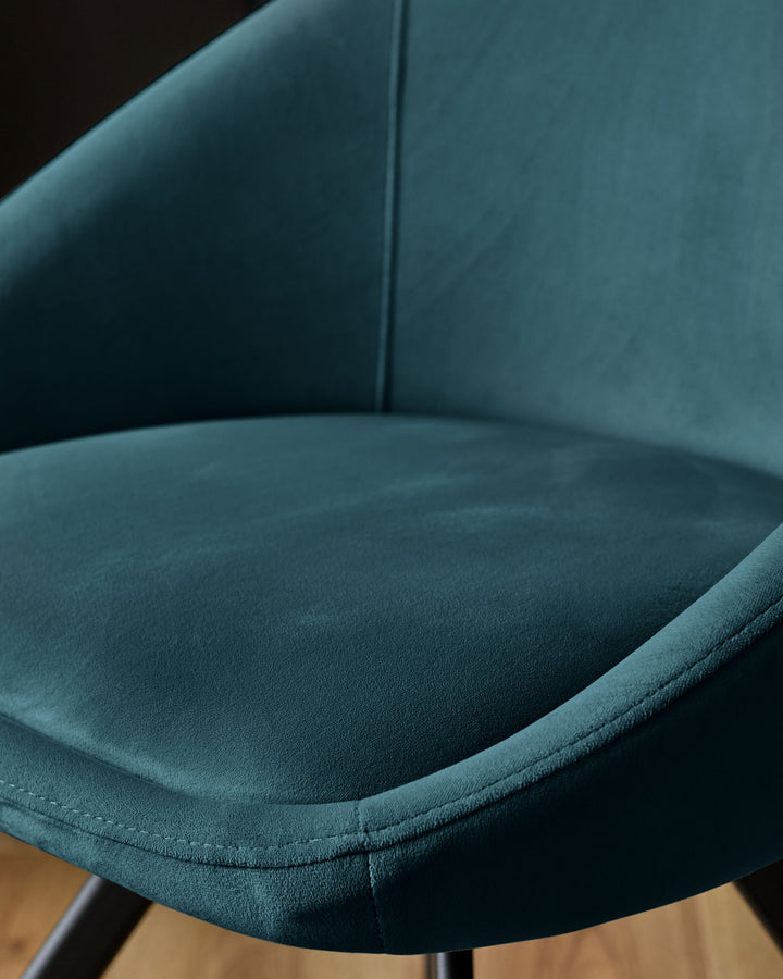 Close-up of dark teal velvet upholstery on Cleo swivel chair, showing curved seat and backrest detail.