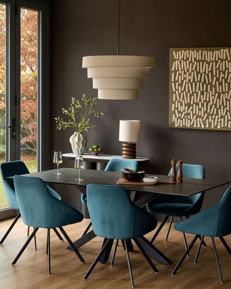 Cleo velvet swivel chair in dark teal, shown in modern dining room setting around dark table with matching chairs.