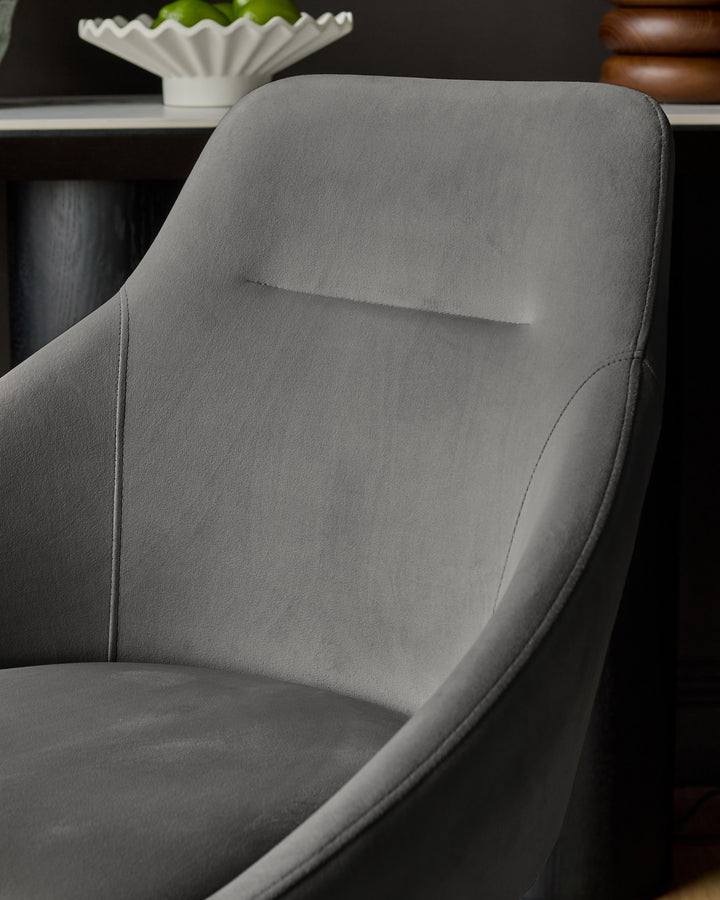 Cleo Velvet Swivel Chair in dark grey, showing curved backrest and seat detail from side angle.
