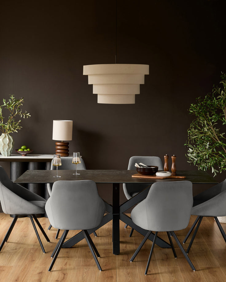 Cleo Velvet Swivel Chair in dark grey, shown in a modern dining room setting at a dark wood table.