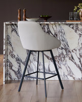 Cleo swivel bar stool in light grey faux leather with black metal legs, shown at marble counter.