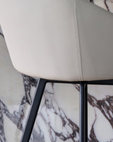 Cleo swivel bar stool in light grey faux leather with black metal frame, close-up detail view.