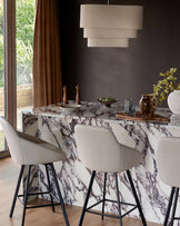 Cleo swivel bar stool in light grey faux leather with black metal legs, shown at marble counter in modern dining setting.