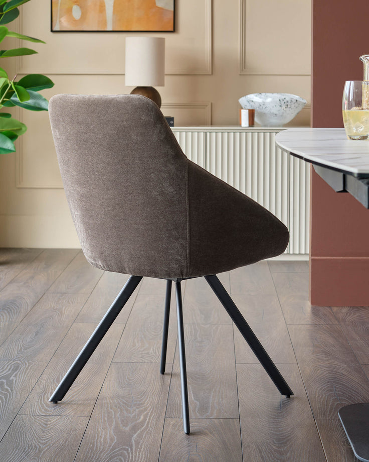 A contemporary dining chair with brown fabric upholstery and black metal legs, positioned in a stylish dining area.