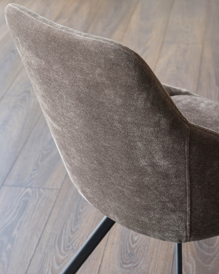 Close-up of a modern, stylish chair with textured fabric upholstery and sleek, dark metal legs.