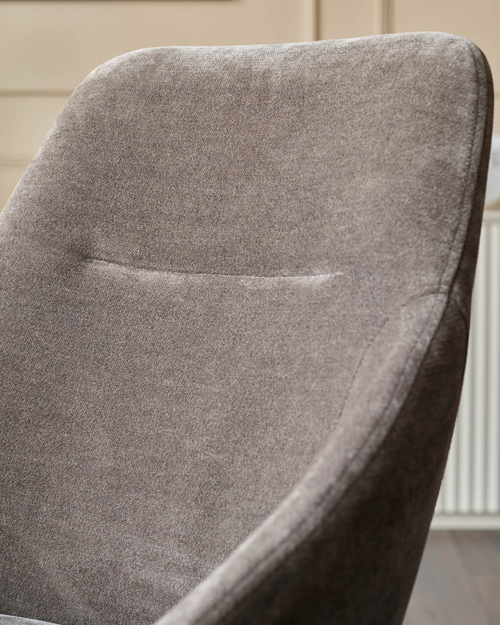 Close-up of a grey upholstered chair. The soft fabric and modern design make it a stylish and comfortable seating option.