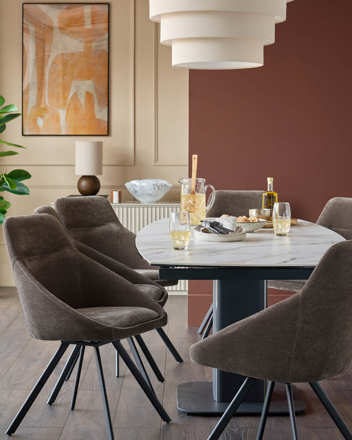 Dining area featuring a round marble-top table and stylish brown fabric chairs with black metal legs.