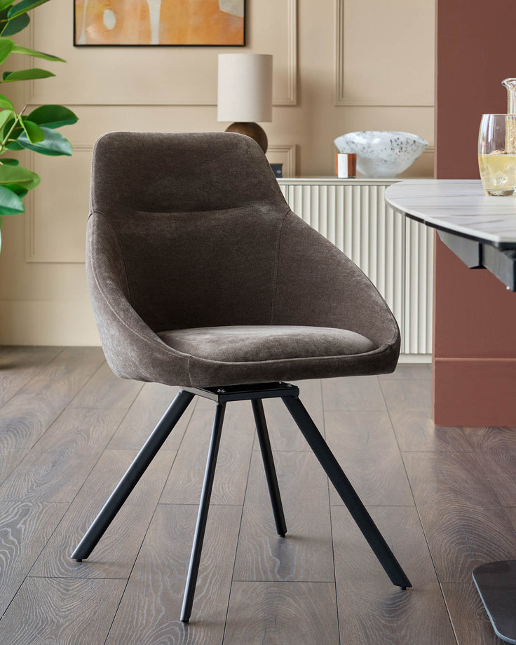 Upholstered swivel chair in grey fabric with a black metal leg frame. Modern and stylish seating for the dining room.