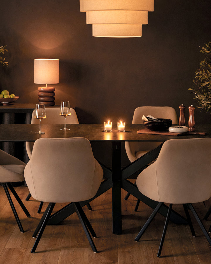 Champagne velvet swivel chair with curved backrest and black metal legs in dining room setting.