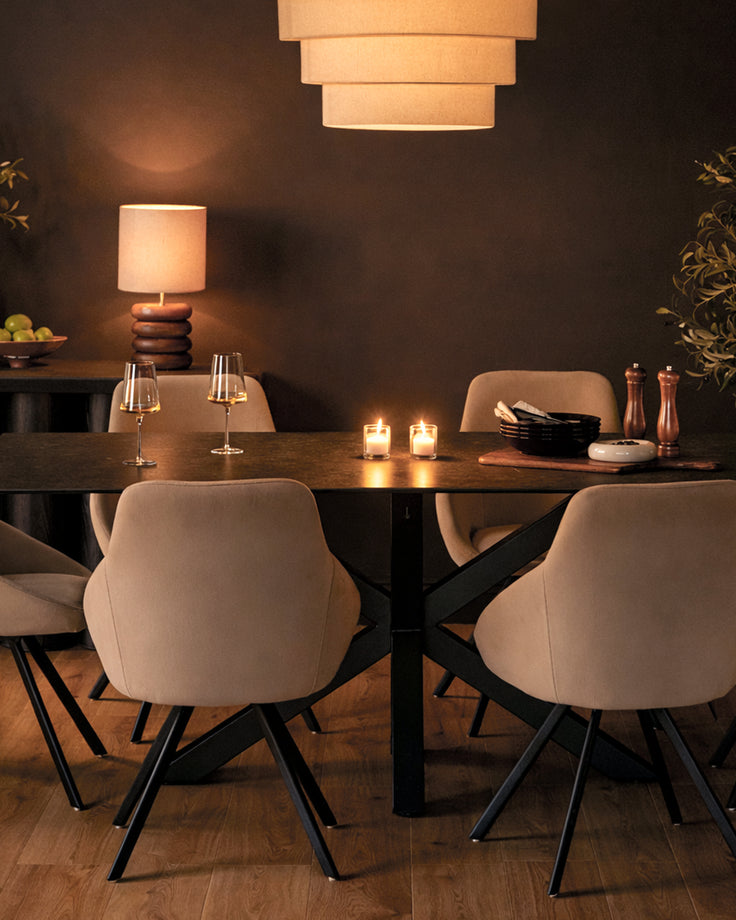 Champagne velvet swivel chair with curved backrest and black metal legs in dining room setting.