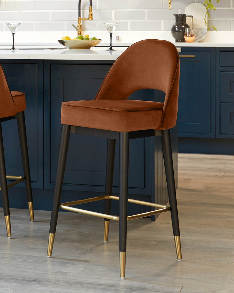 Elegant contemporary bar stools with plush burnt orange velvet upholstery and curved backrests, featuring black metal legs tipped with gold accents and a circular gold footrest.