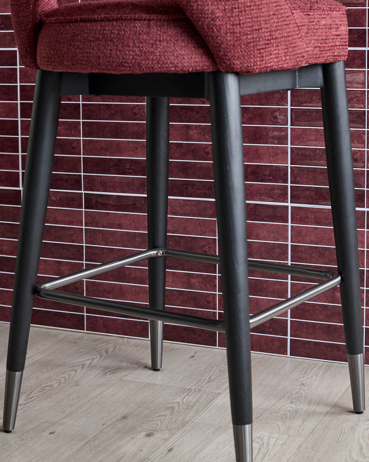 Burgundy bar stool with black legs and a silver footrest. Part of a modern kitchen furniture set.