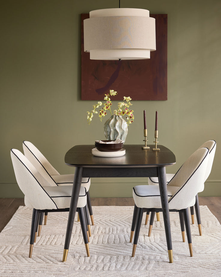 Clover ivory fabric dining chair with black frame and brass-capped legs, shown in dining room setting.