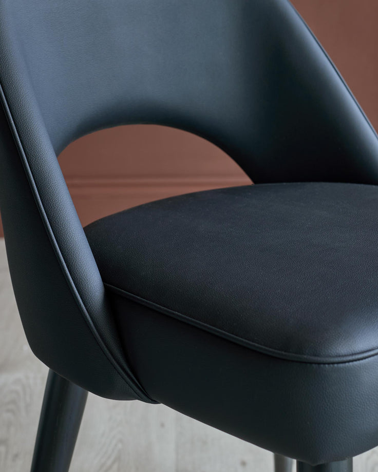 A modern, black, faux leather chair with a curved back and minimalist design, perfect for adding style to any room.