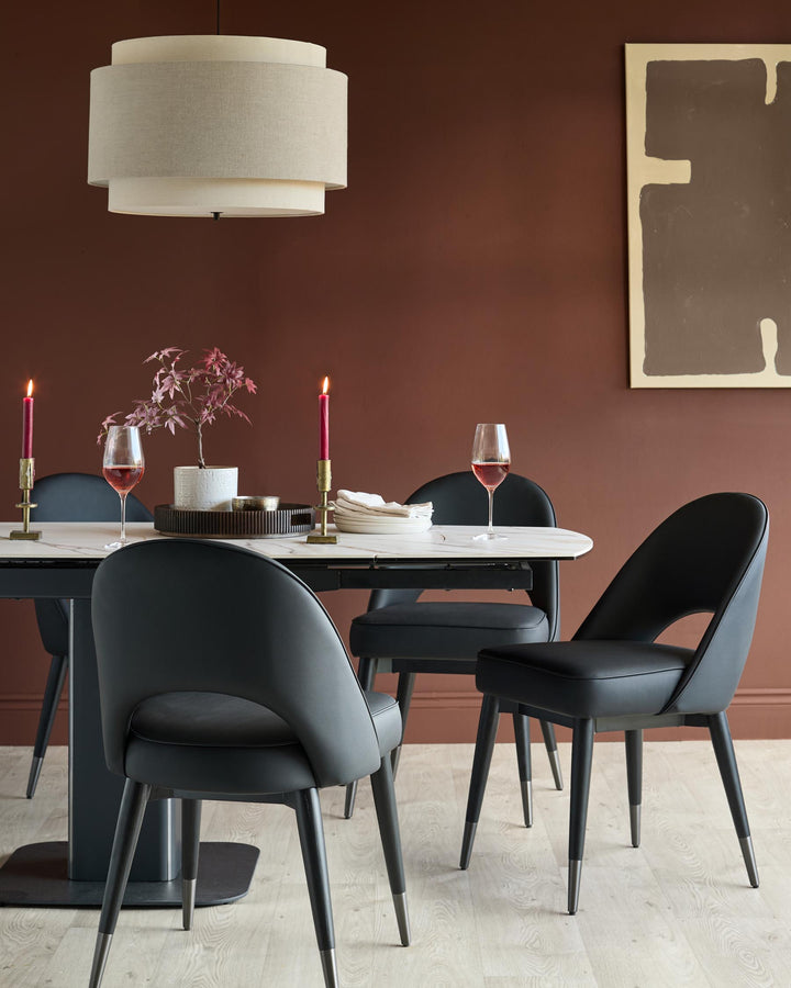 A dining table with marble top, surrounded by stylish black leather chairs, and a modern pendant light above.