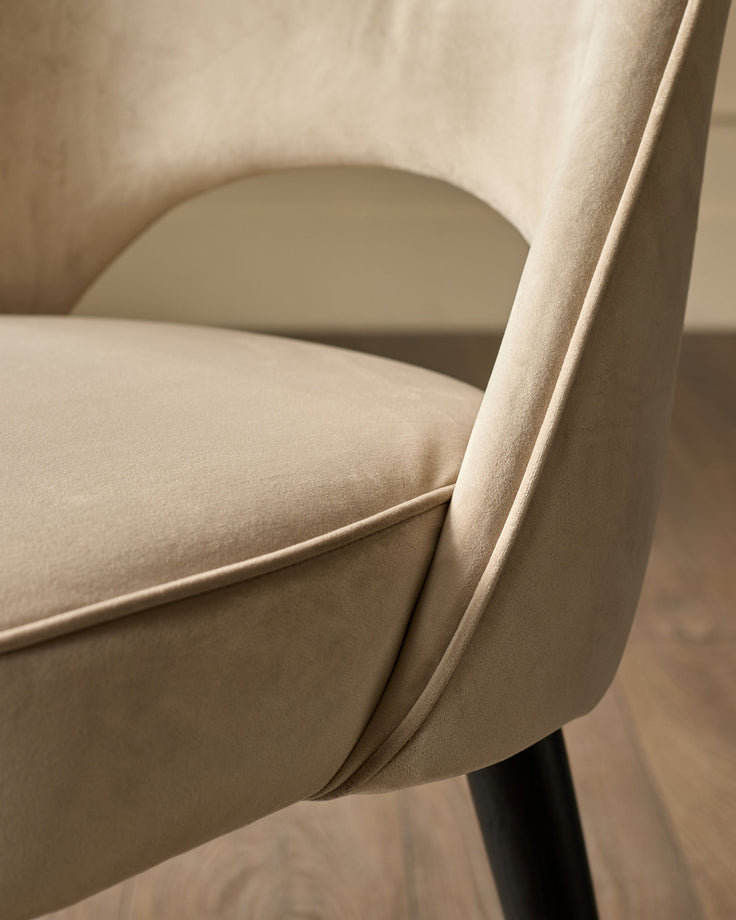 Champagne velvet dining chair detail showing curved backrest, seat, and black leg.