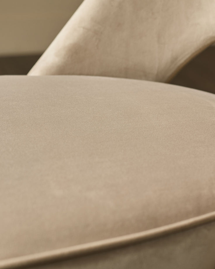 Clover velvet dining chair in champagne, close-up detail of curved seat and backrest upholstery.