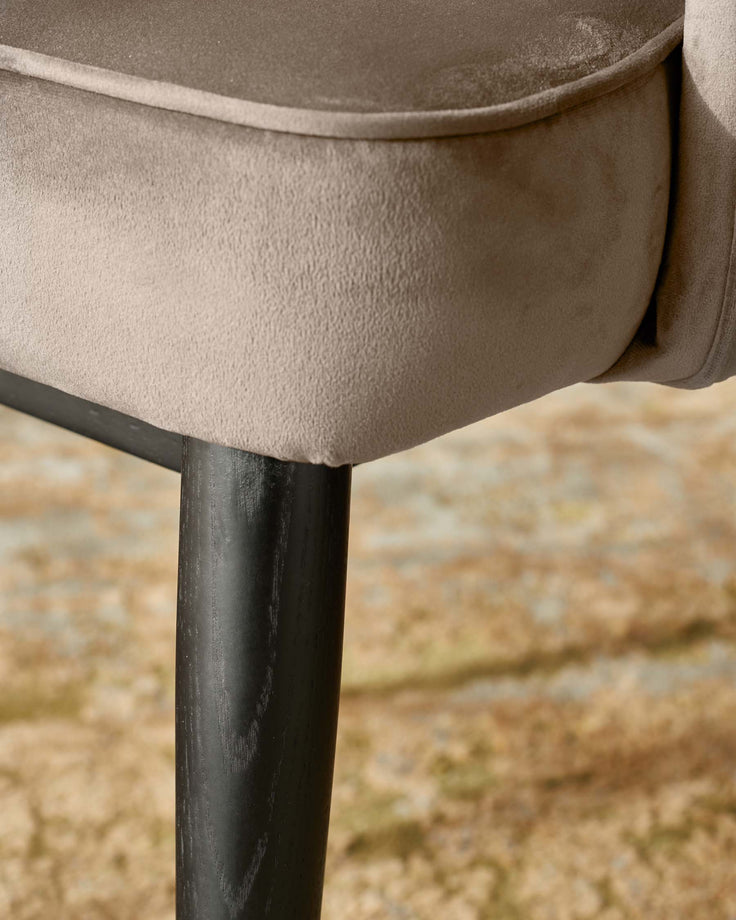 Close-up of a chair leg and part of the seat, showing the upholstered fabric and dark wood leg.
