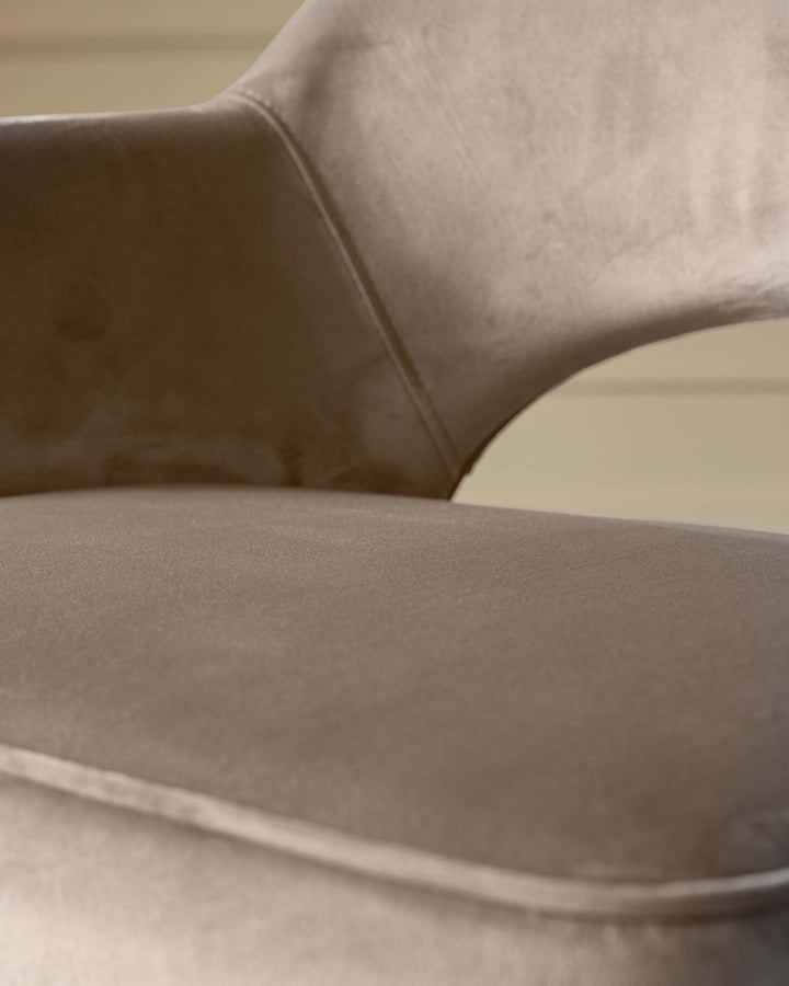 Close-up of a stylish, modern chair. The neutral-toned velvet fabric adds a touch of luxury.