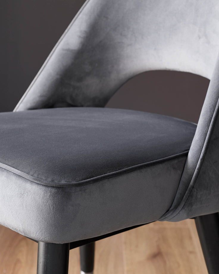 Clover velvet dining chair in dark grey with curved backrest and stainless steel legs, side detail view.
