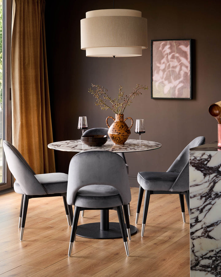 Clover velvet dining chair in dark grey with stainless steel leg caps, shown in a styled dining room setting.