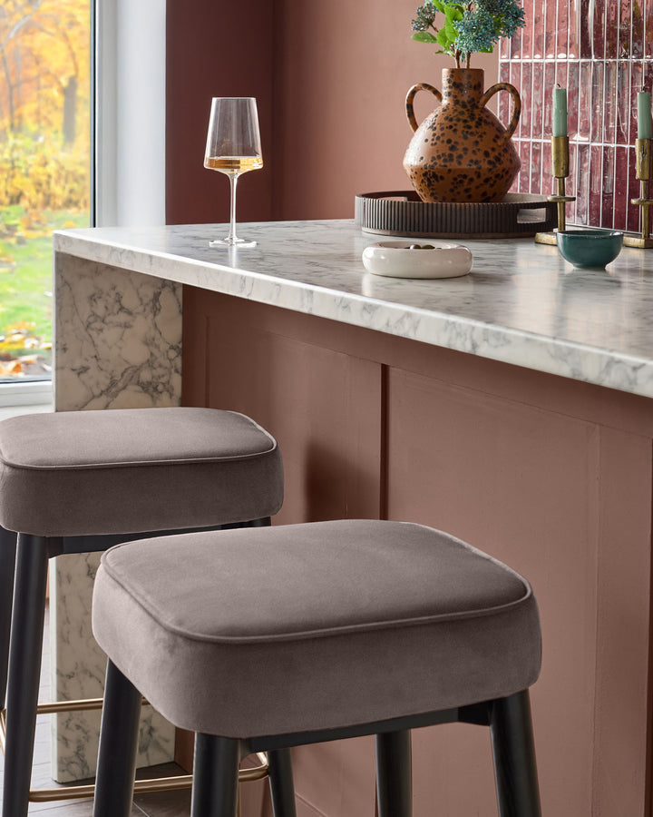 Mocha velvet backless bar stools at marble countertop in contemporary kitchen with warm taupe walls.