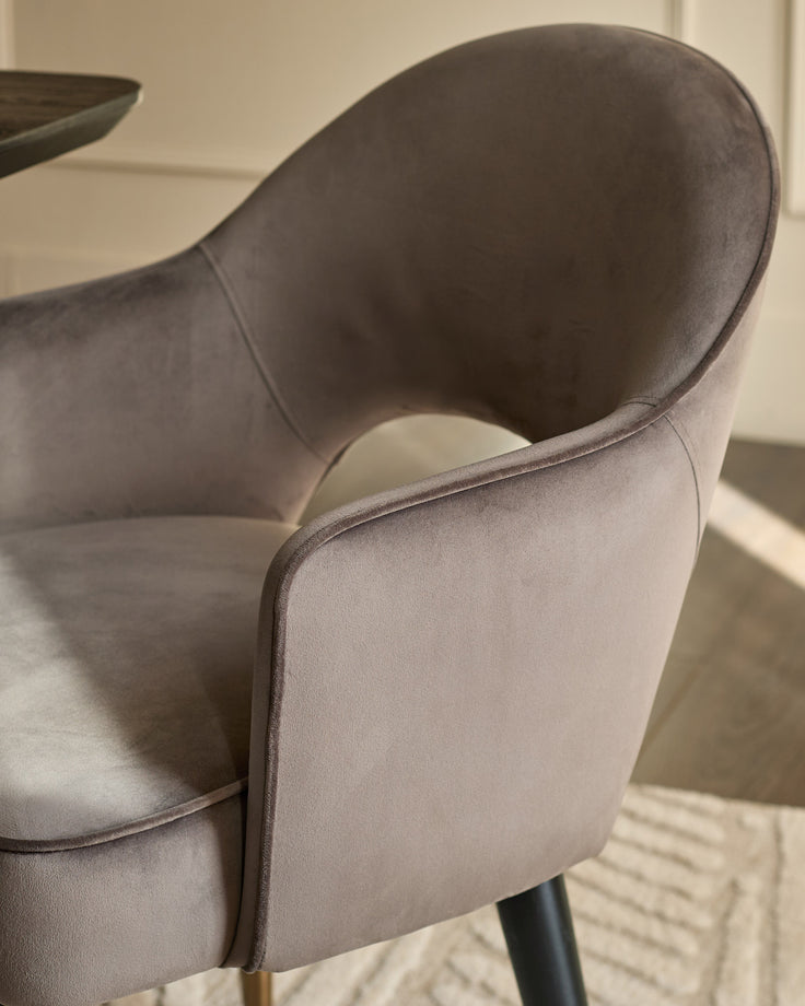 Clover velvet dining armchair in mocha, showing curved backrest and black wooden legs in close-up detail.