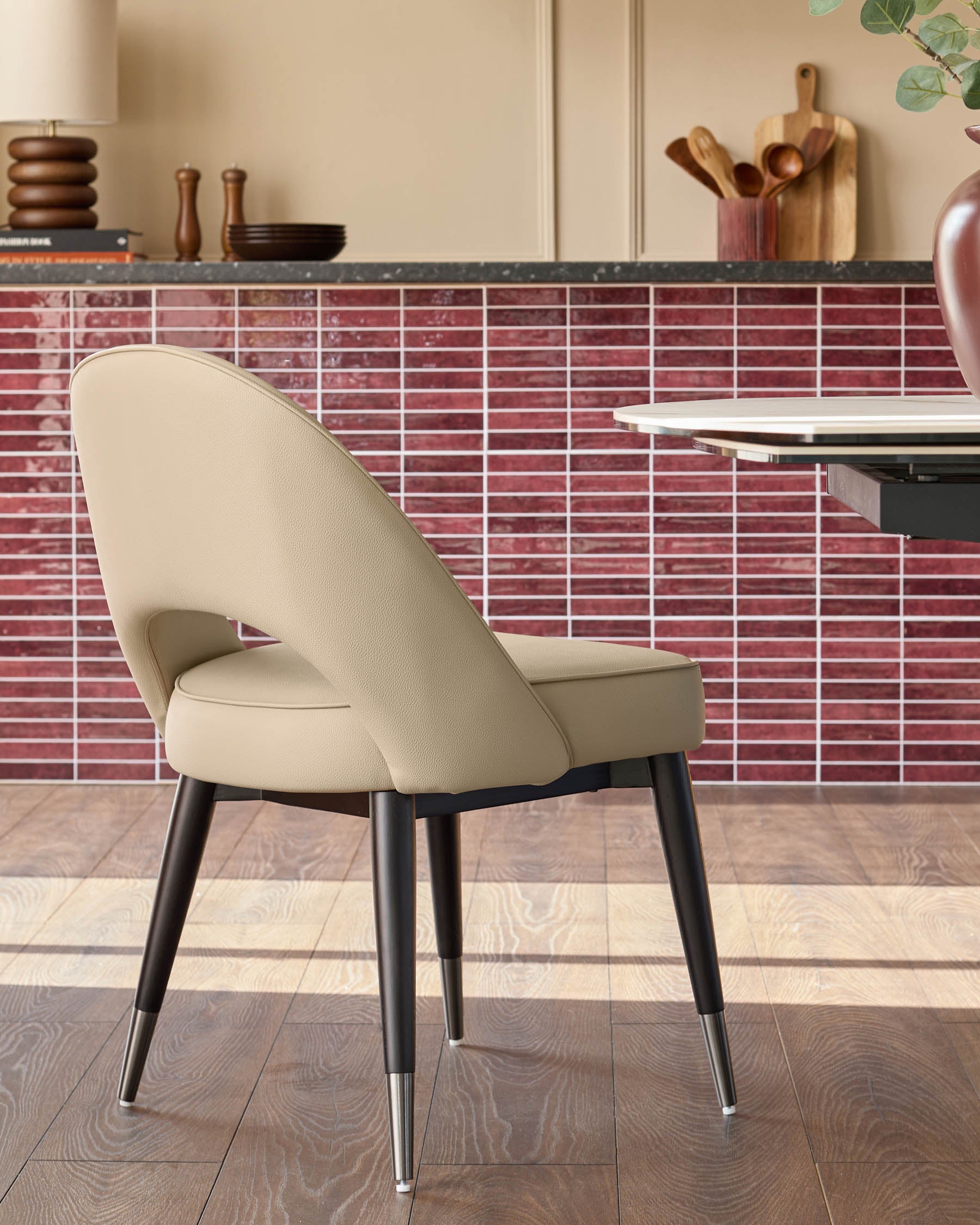 A stylish chair with a padded seat and back, complemented by sleek, dark legs with metallic tips.