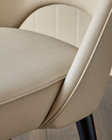Close-up of a stylish, modern chair with cream leather upholstery and sleek black legs, showcasing its elegant design and comfort.