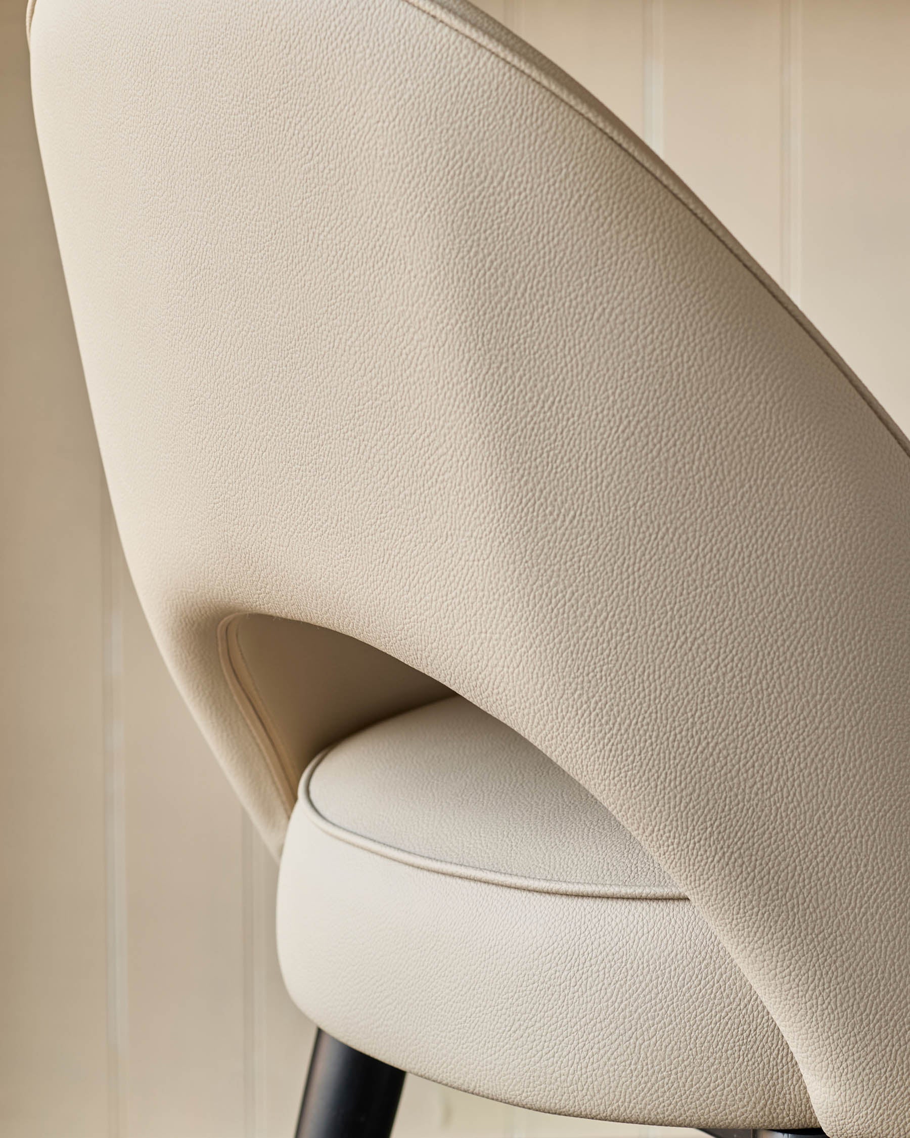 Close-up of a cream coloured chair with a leather-like texture, showcasing its design and quality.